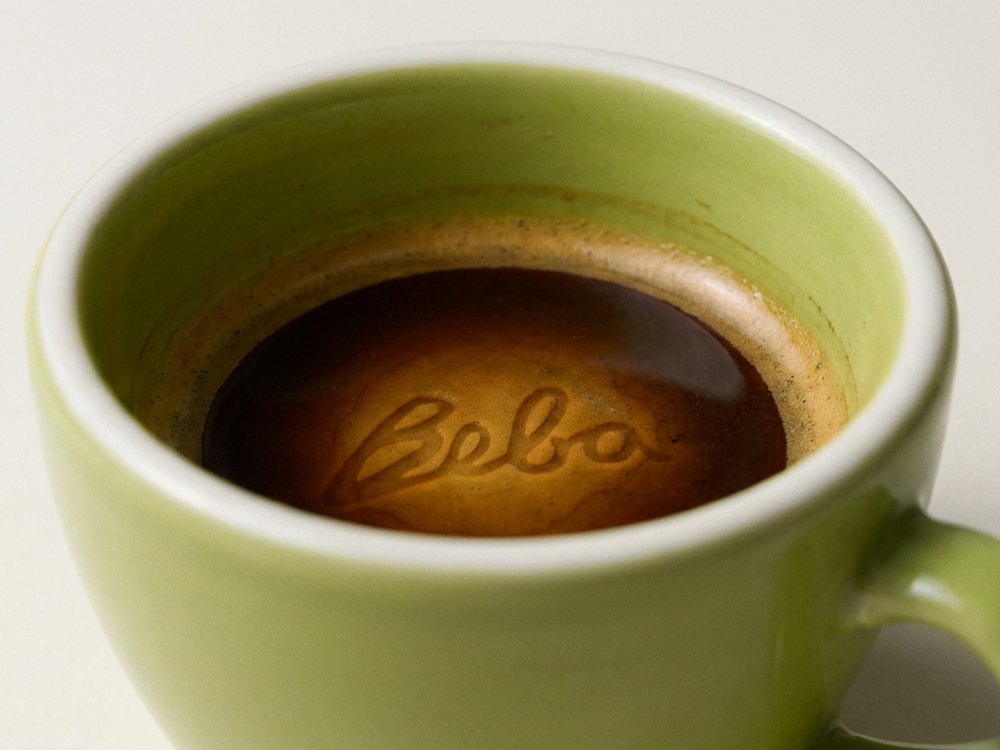 Xícara verde da Beba com o logo desenhado na crema